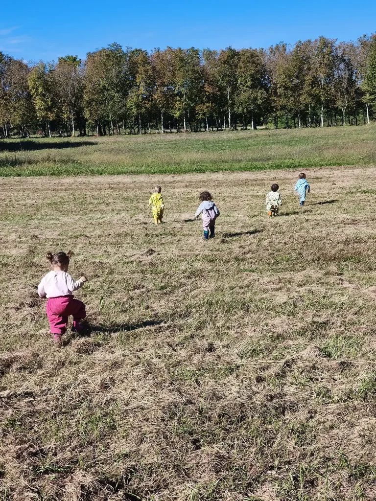 Un gruppo di bambini mentre corre in un campo, alla scoperta della natura