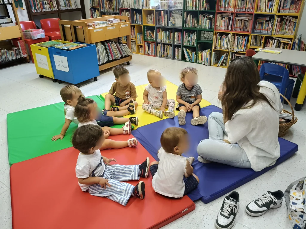 Un gruppo di bambini seduto in cerchio mentre ascolta una storia raccontata dalla maestra